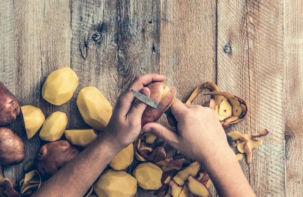 A Person is Peeling Potatoes on a Wooden Table — Collis Care In Dundowran, QLD