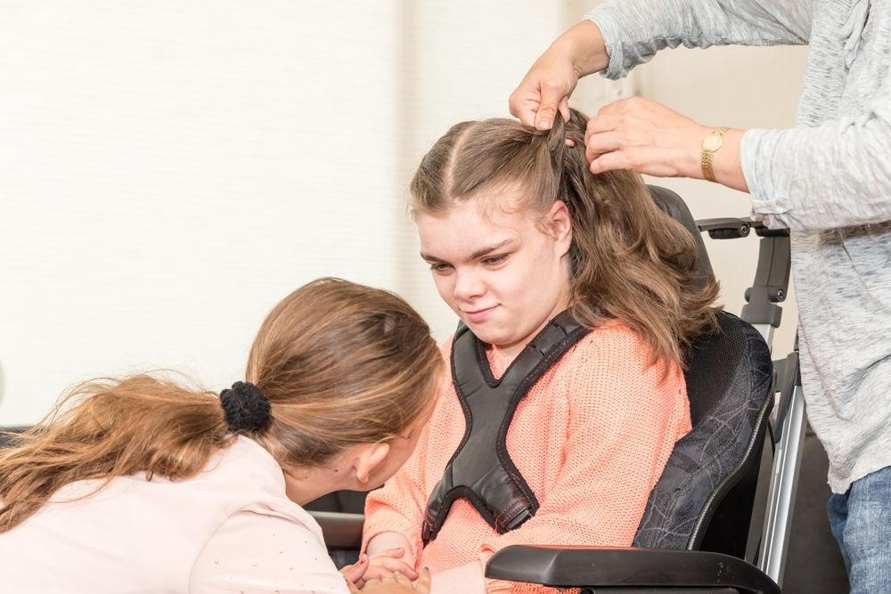 A Woman is Putting a Harness on a Girl in a Wheelchair — Collis Care In Dundowran, QLD