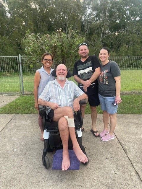 Four People Pose Outdoors Around Person in Wheelchair — Collis Care In Dundowran, QLD
