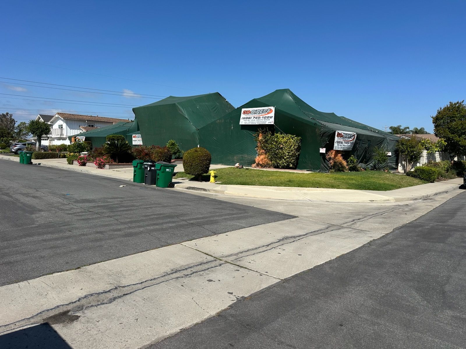 Building wrapped in green tarp on a corner lot; signs visible.
