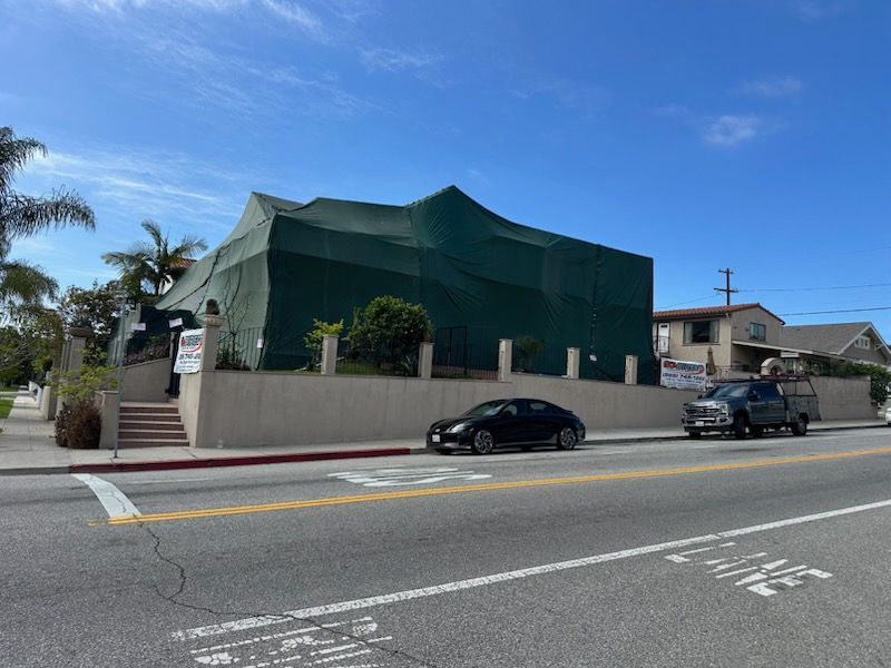 Green tent covering a building, likely for pest control. 