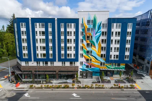 Woman wearing a green headband, smiling, with a high bun and earbuds.