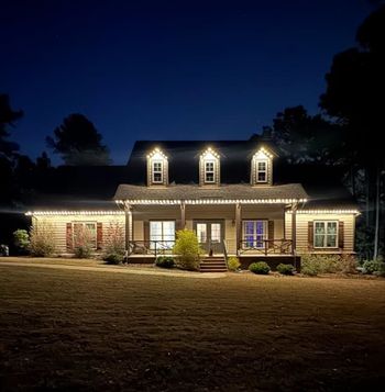 A large house is lit up at night with christmas lights.