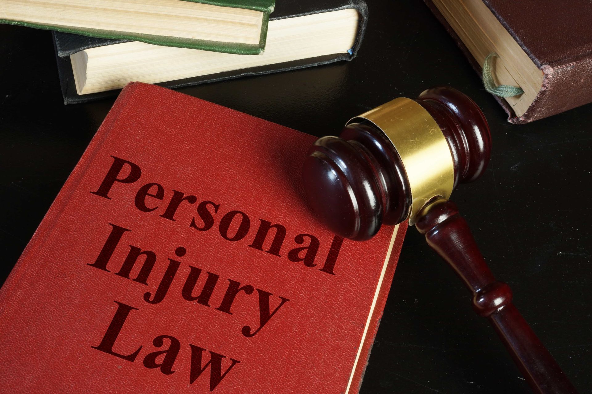 Personal Injury Law book with gavel and stacked books on desk