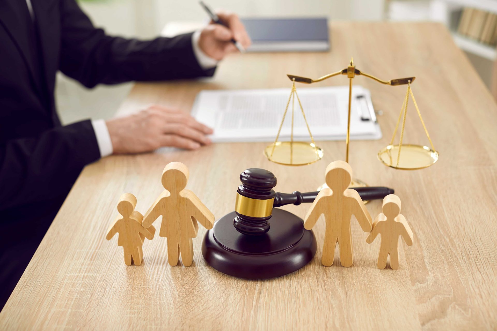 Lawyer’s desk with gavel, scales of justice, and family figurines beside a document