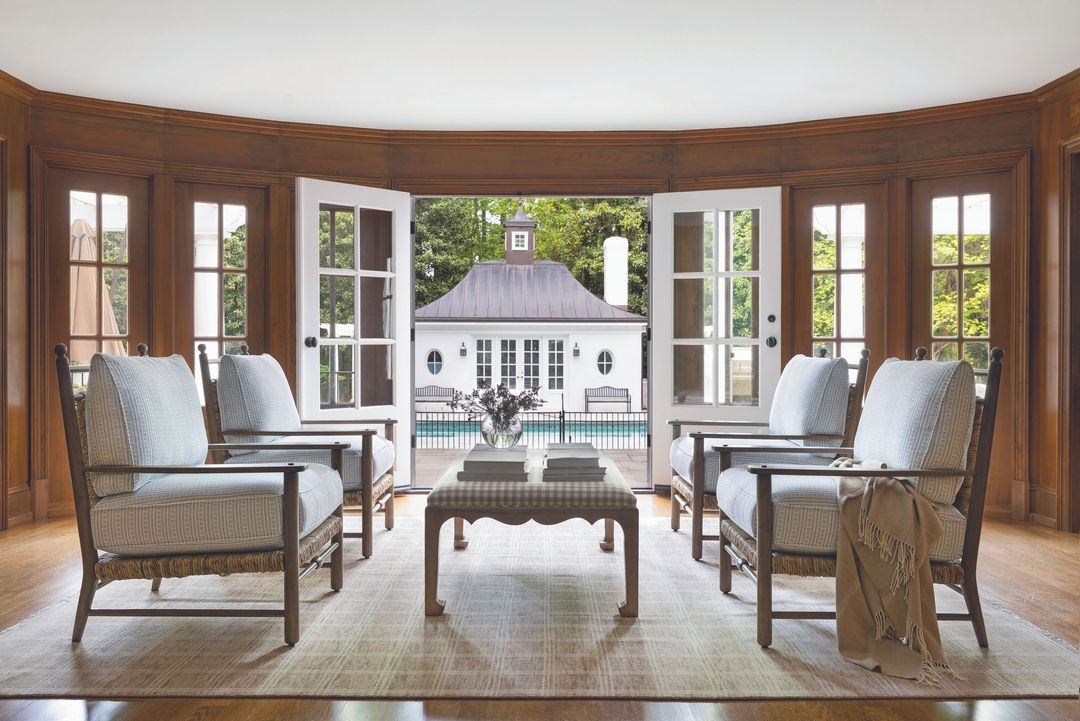 Living room with open doors to a pool. Brown wood trim, white doors, and four chairs face a small table.