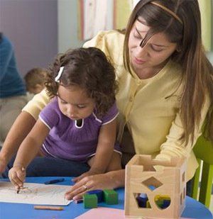 A woman is helping a little girl draw on a piece of paper.