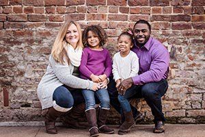 A family is posing for a picture in front of a brick wall.