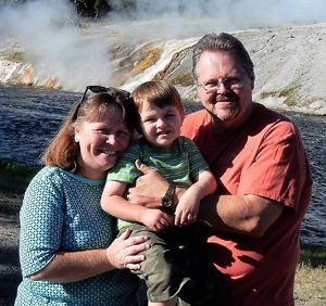 A man and woman holding a little boy in front of a waterfall