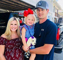 A man and a woman are standing next to a little girl holding a stuffed animal.