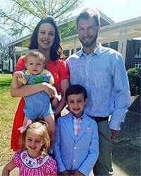 A family is posing for a picture in front of a house.