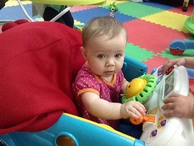 A baby is sitting in a walker playing with a toy