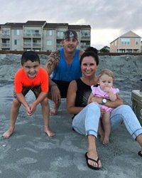 A family is posing for a picture on the beach.