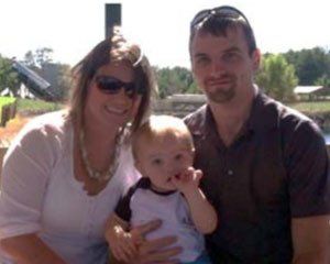 A man and a woman are posing for a picture with a baby