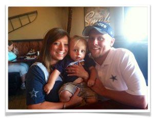 A man wearing a cowboys hat is holding a baby