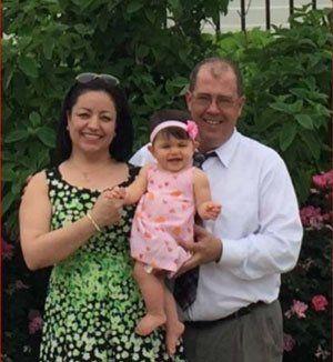 A man and woman are holding a baby girl in their arms.