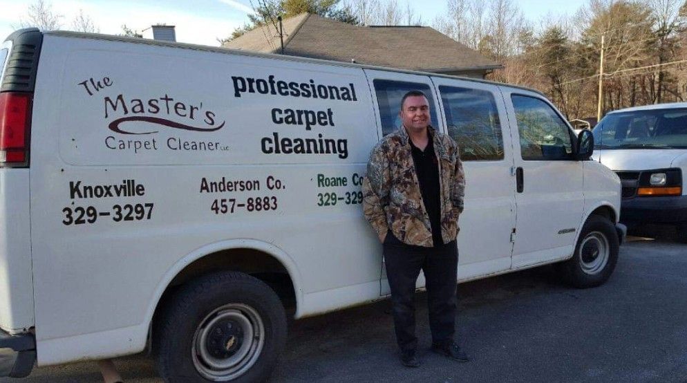 Man in camo jacket stands beside a white van for 