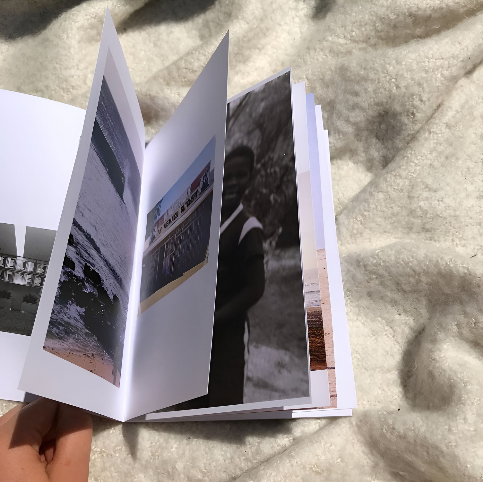 Hand Holding Open Photo Book with Ocean, Person, and Boat Images — Digi Print Pro in Brunswick Heads, NSW