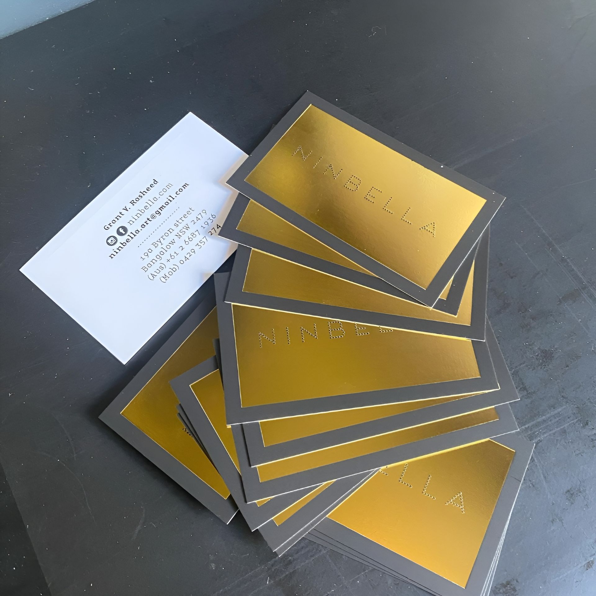 Pile of Gold and Black Business Cards Next to A White Card with Contact Information — Digi Print Pro in Bangalow, NSW