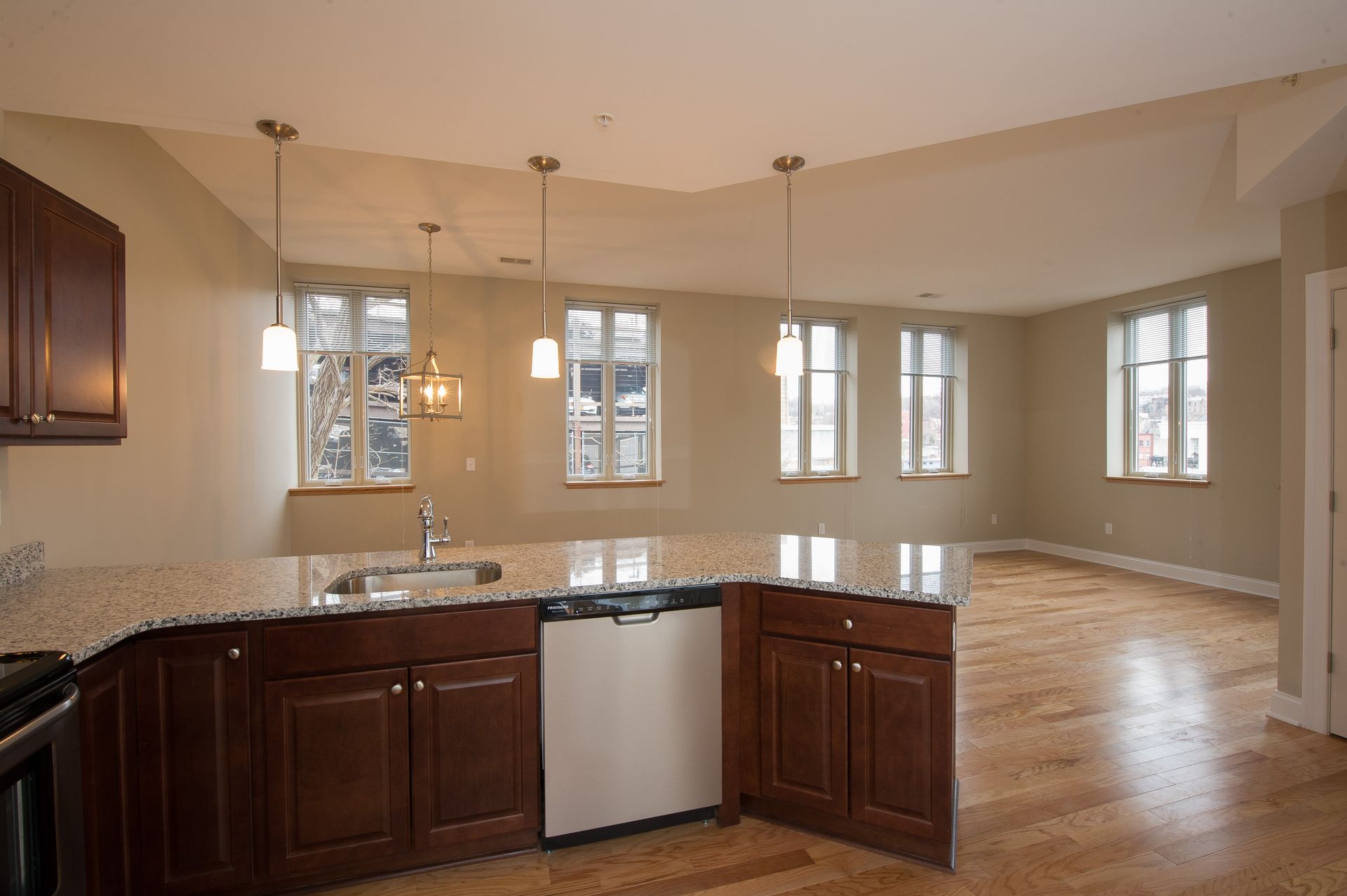 An empty kitchen with granite counter tops and stainless steel appliances