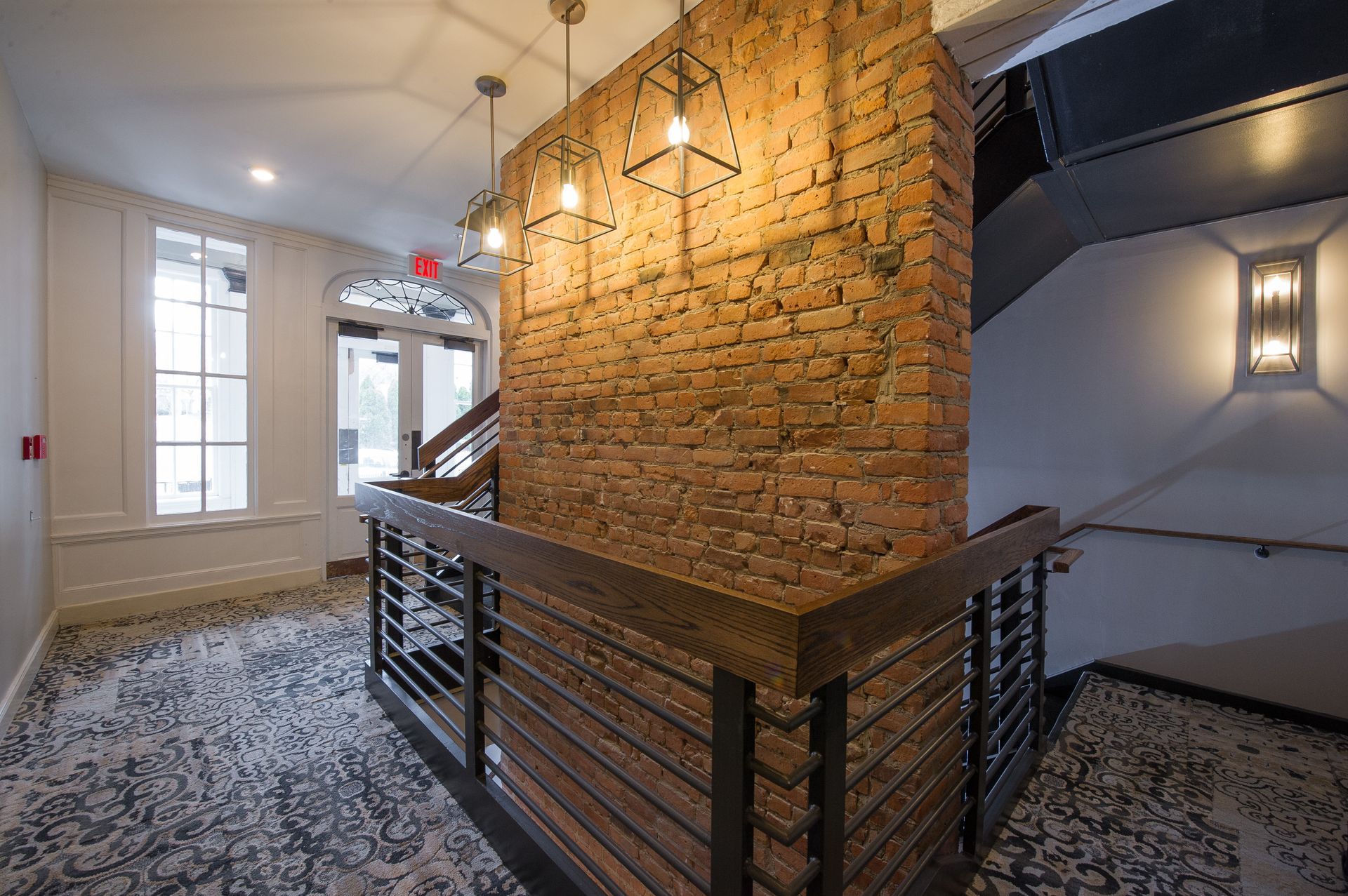 A hallway with a brick wall and stairs in a building.