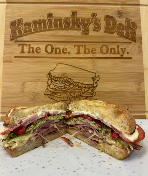 A sandwich is cut in half on a wooden cutting board.