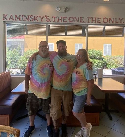 A group of people posing for a picture in front of a sign that says kaminsky 's the one the only