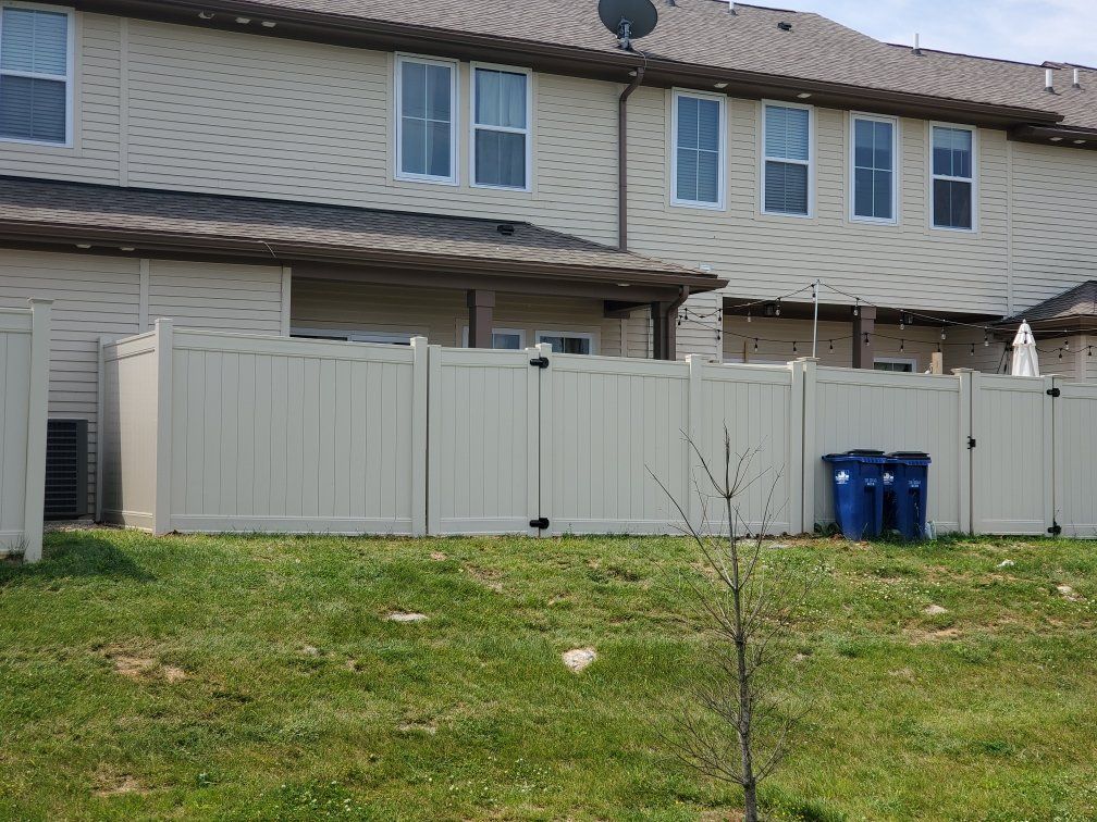 There is a white fence in the backyard of a house.