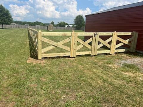 A wooden fence is sitting in the middle of a lush green field.