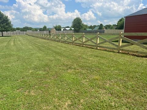 A wooden fence surrounds a lush green field.