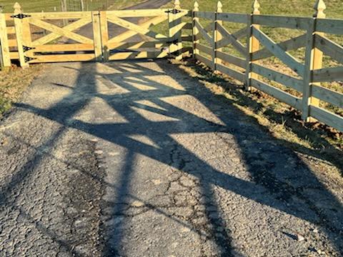 A wooden gate is sitting on the side of a road.