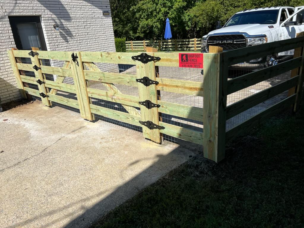 A white truck is parked in front of a wooden fence.