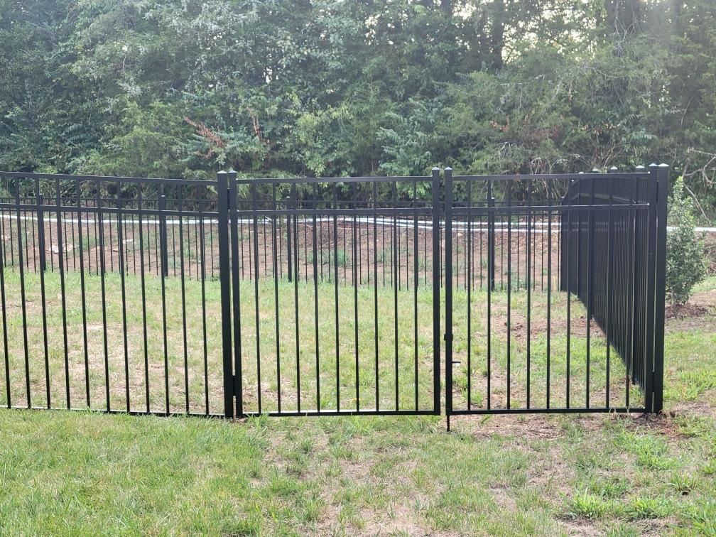 A black metal fence surrounds a lush green field
