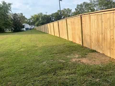 A wooden fence surrounds a lush green field.