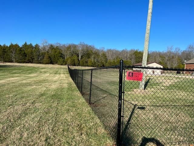 A black chain link fence surrounds a baseball field.