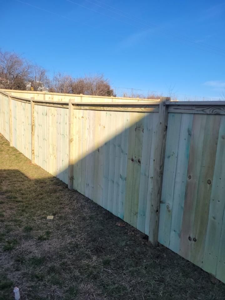 A wooden fence in a backyard with a blue sky in the background.