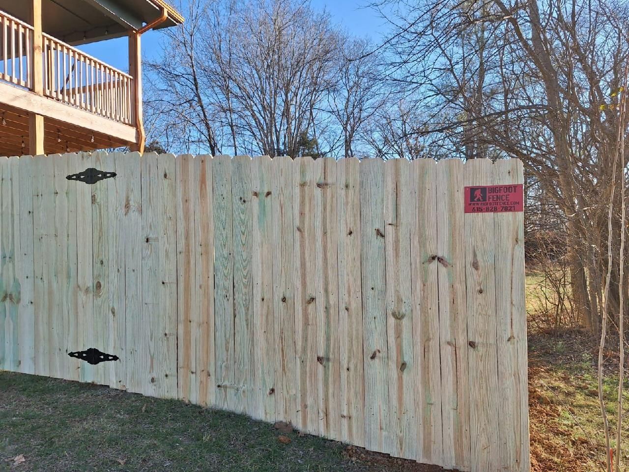 A wooden fence in front of a house with a balcony.