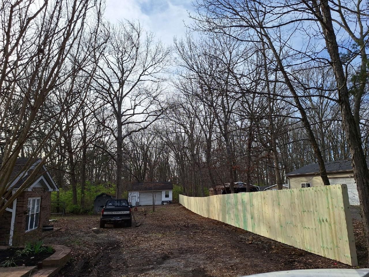 A wooden fence is surrounding a house in the woods.