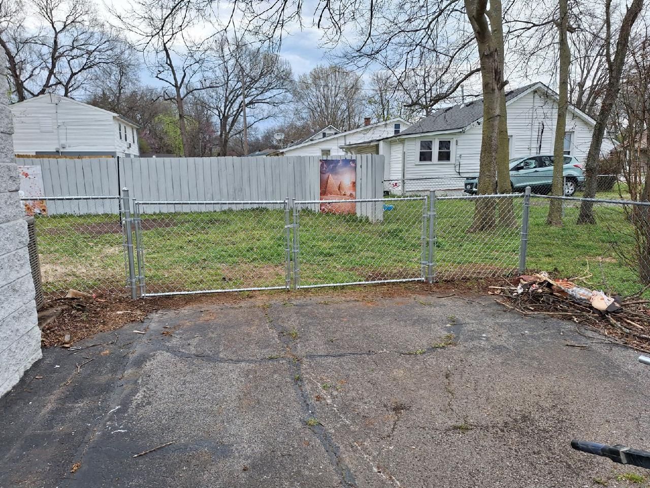 A chain link fence surrounds a driveway in front of a house.