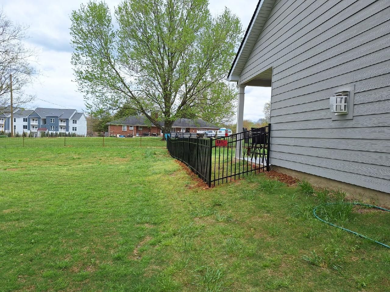 A fence is surrounding a house in a grassy yard.