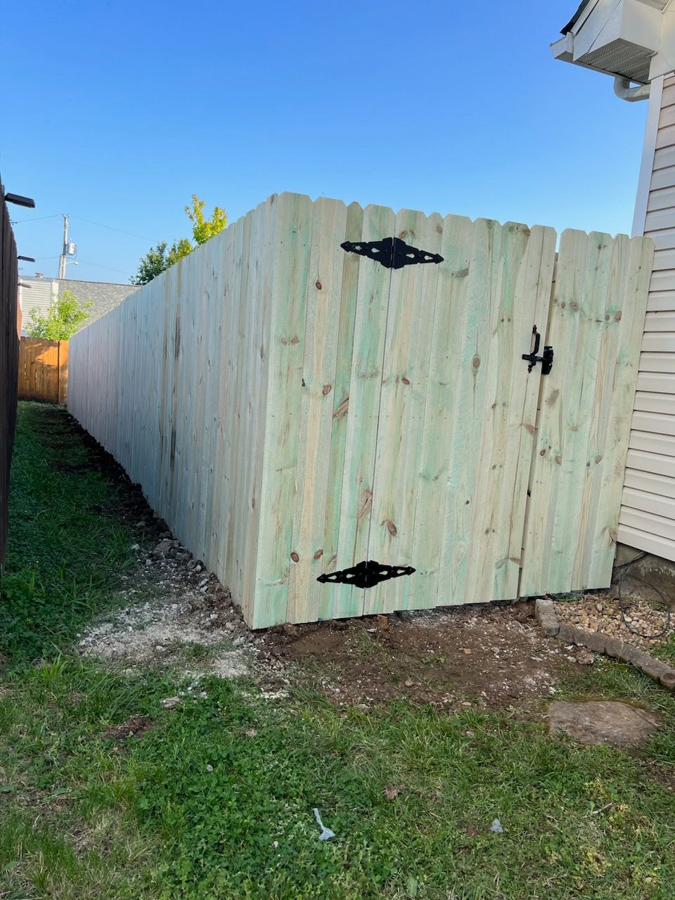 A wooden fence with a gate in the backyard of a house.