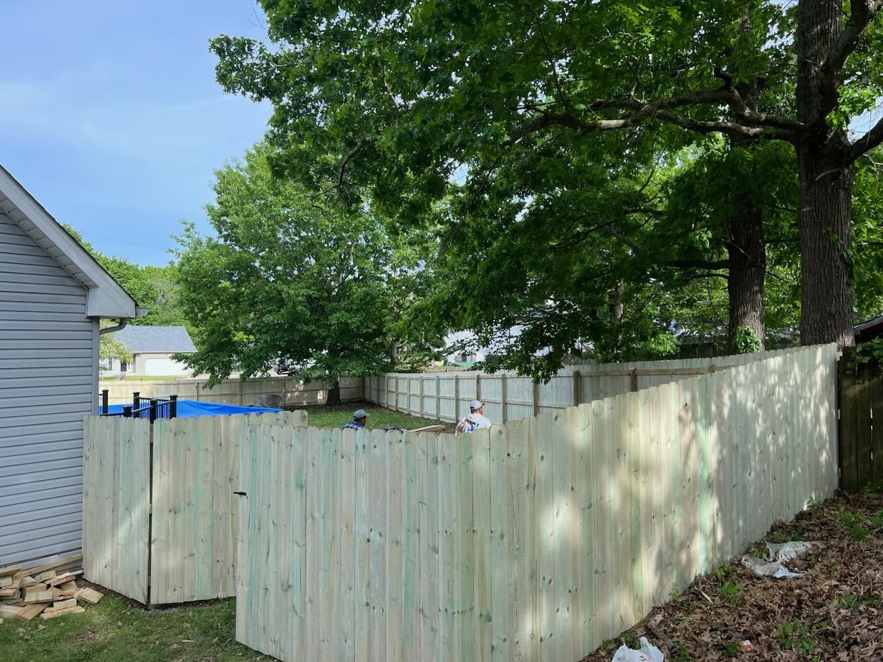 A wooden fence is being built in the backyard of a house.