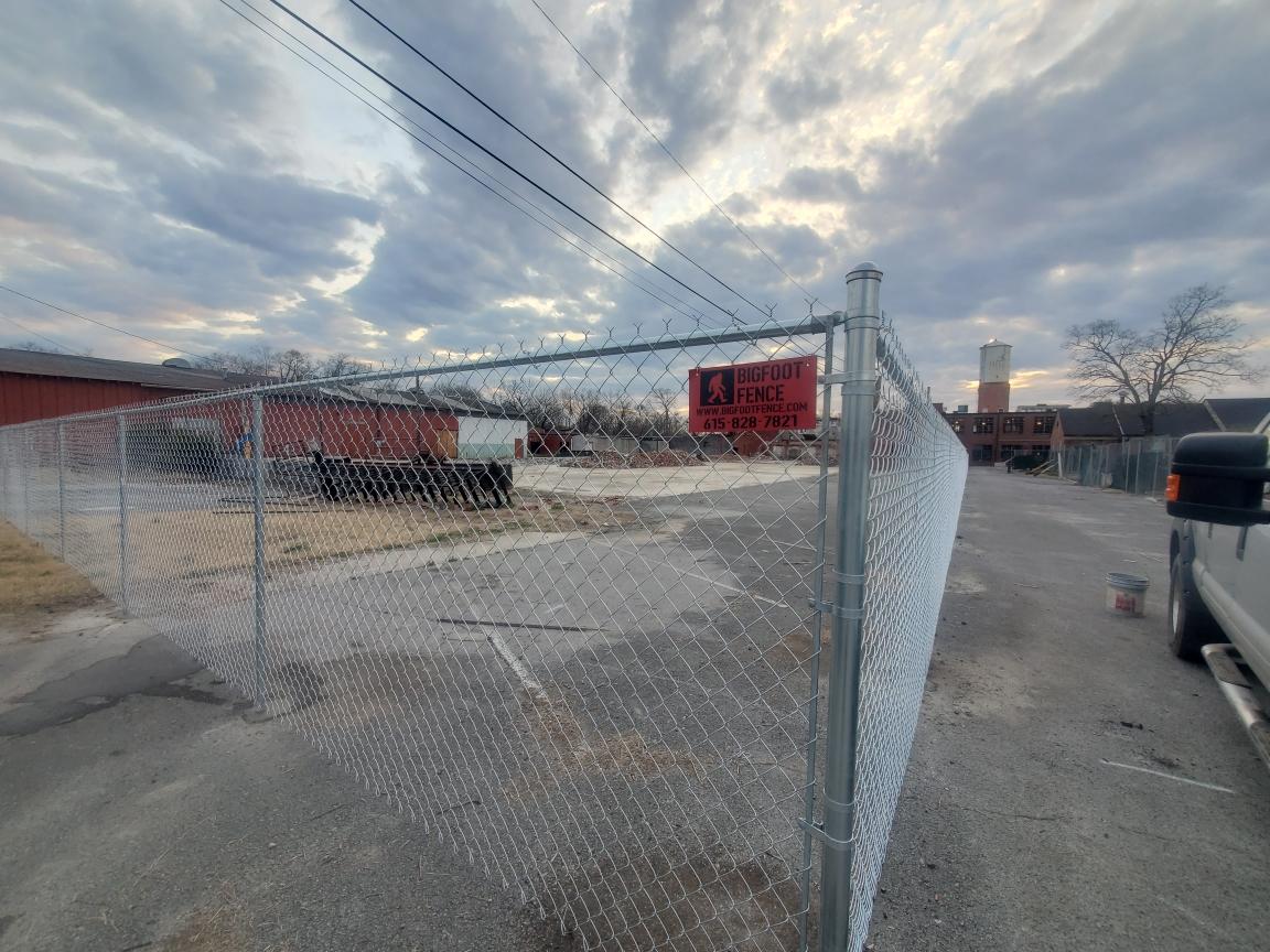 A chain link fence is surrounding a parking lot.