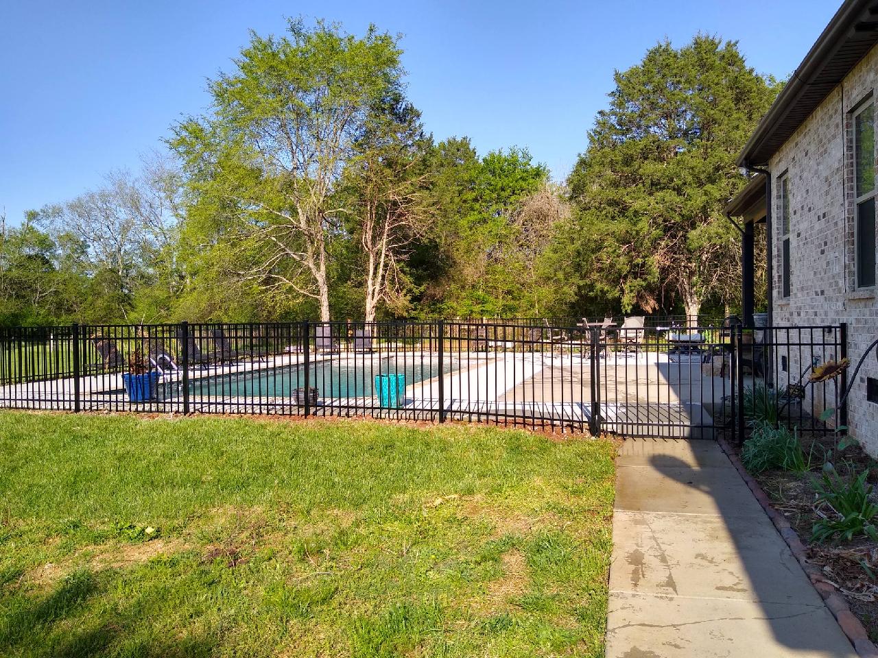 A house with a fence around it and a pool in the backyard.