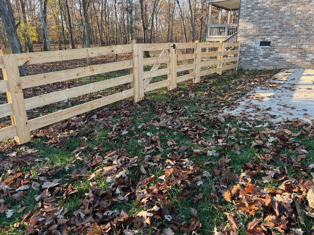 A wooden fence is in the backyard of a house.