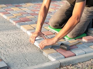 Masonry Construction — Construction Worker Laying Sidewalk Tiles in the Yard of the House in Louisville, KY