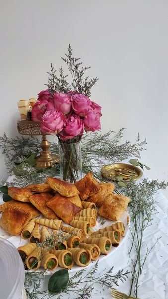 Long table set for event, with flower arrangements, and outdoor lights.