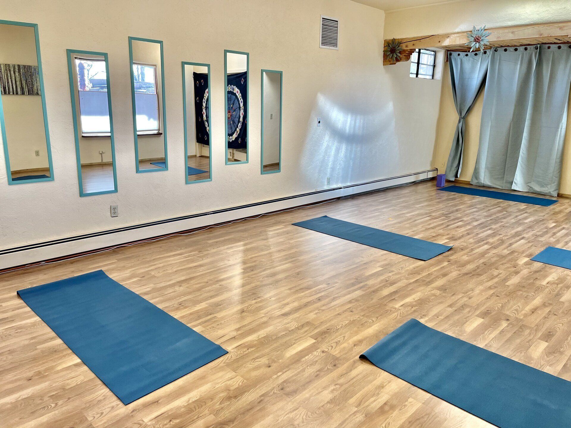 A room with blue yoga mats and mirrors on the wall