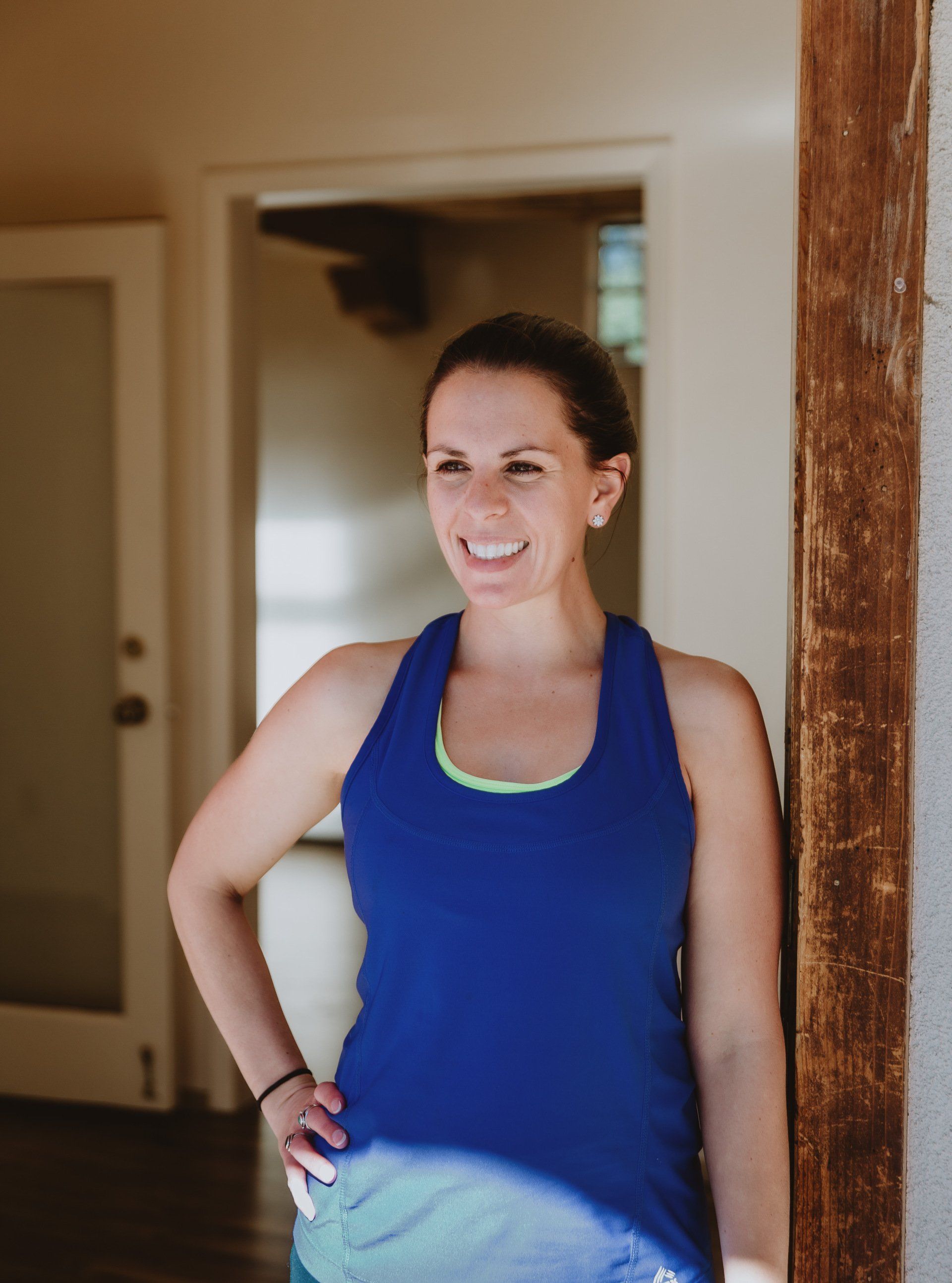 A woman in a blue tank top is standing in front of a door.