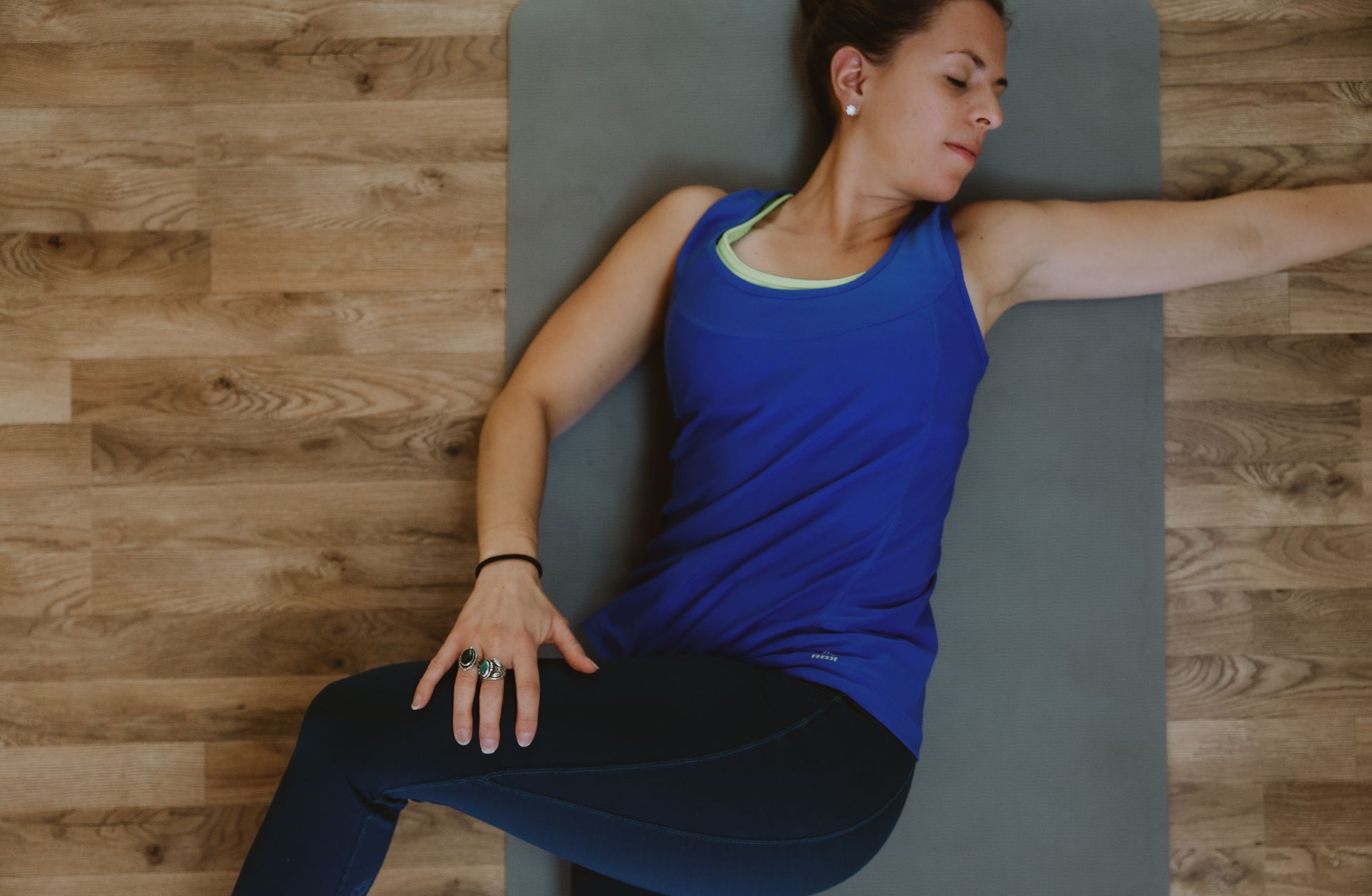 A woman is laying on a yoga mat with her arms outstretched.